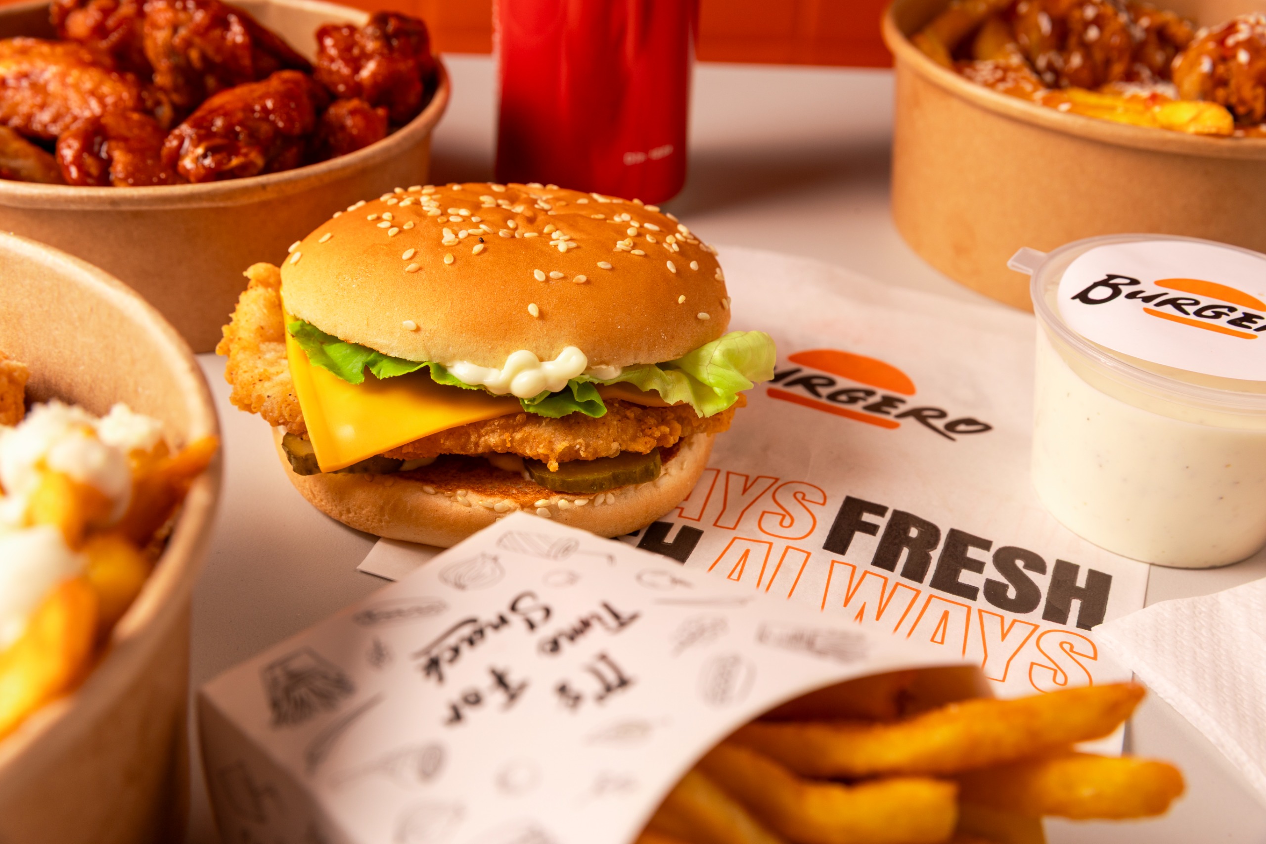 Crispy burger Burgero cu cheddar și salată, alături de aripioare
